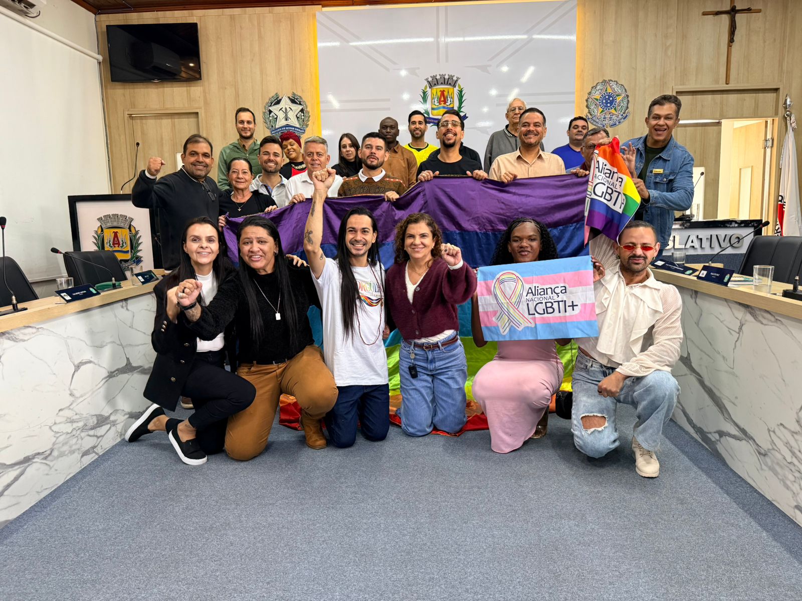 Integrantes e apoiadores do Núcleo LGBTI+ de Araguari reunidos na Câmara Municipal, empunhando bandeiras da diversidade e da Aliança Nacional LGBTI+.
